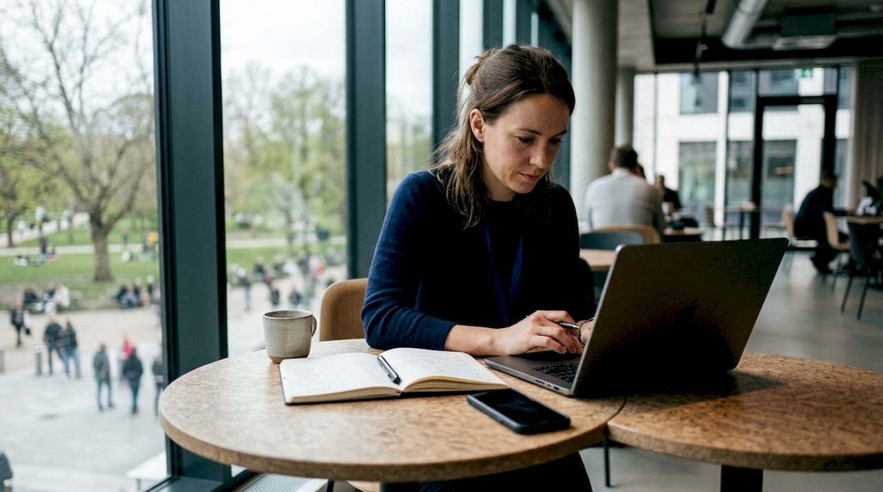 En kvinna sitter djupt koncentrerad med sitt arbete på ett modernt coworkingkontor mitt i stan.