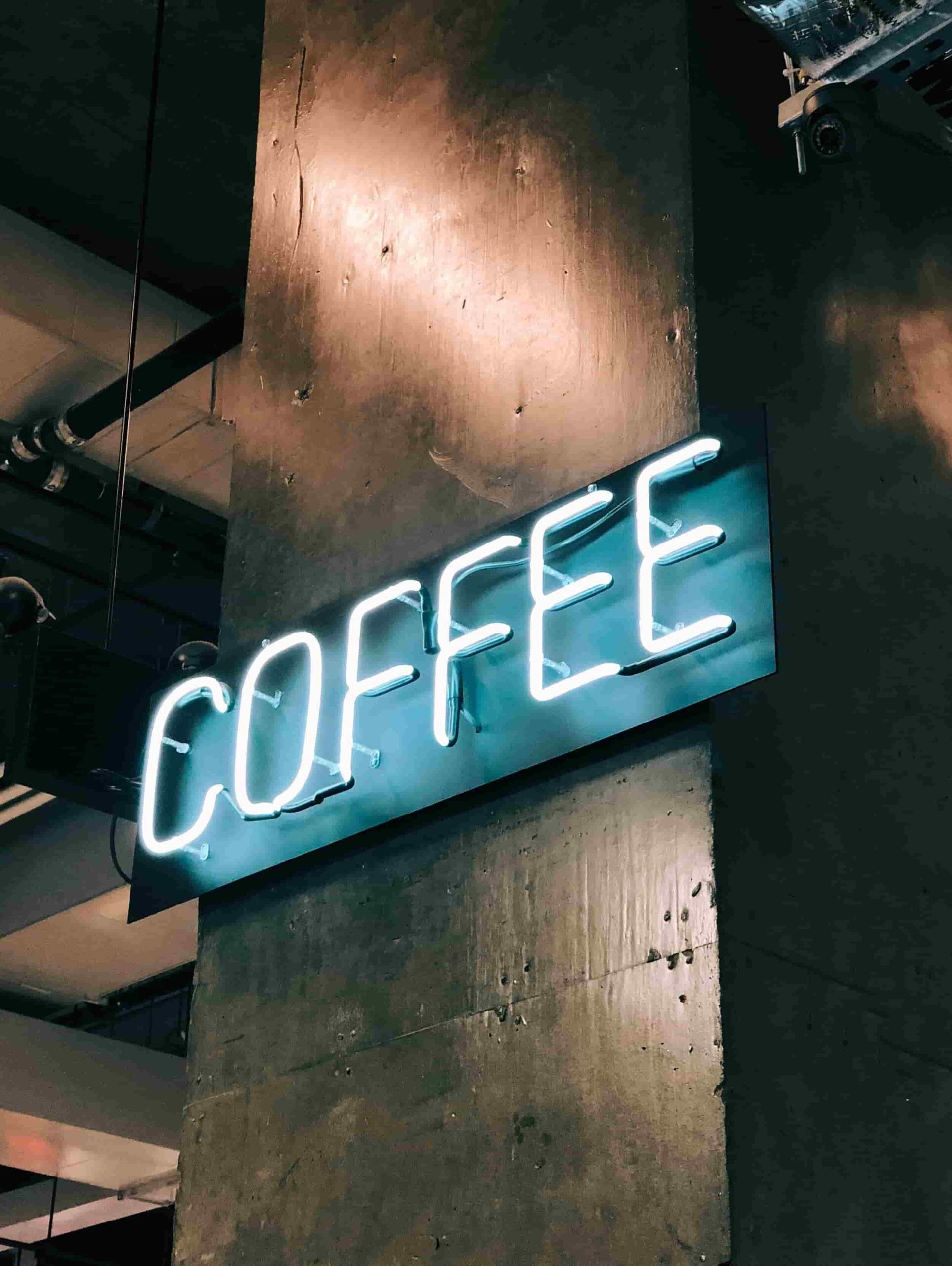Neonskylt med texten Coffee på en tegelfasad
