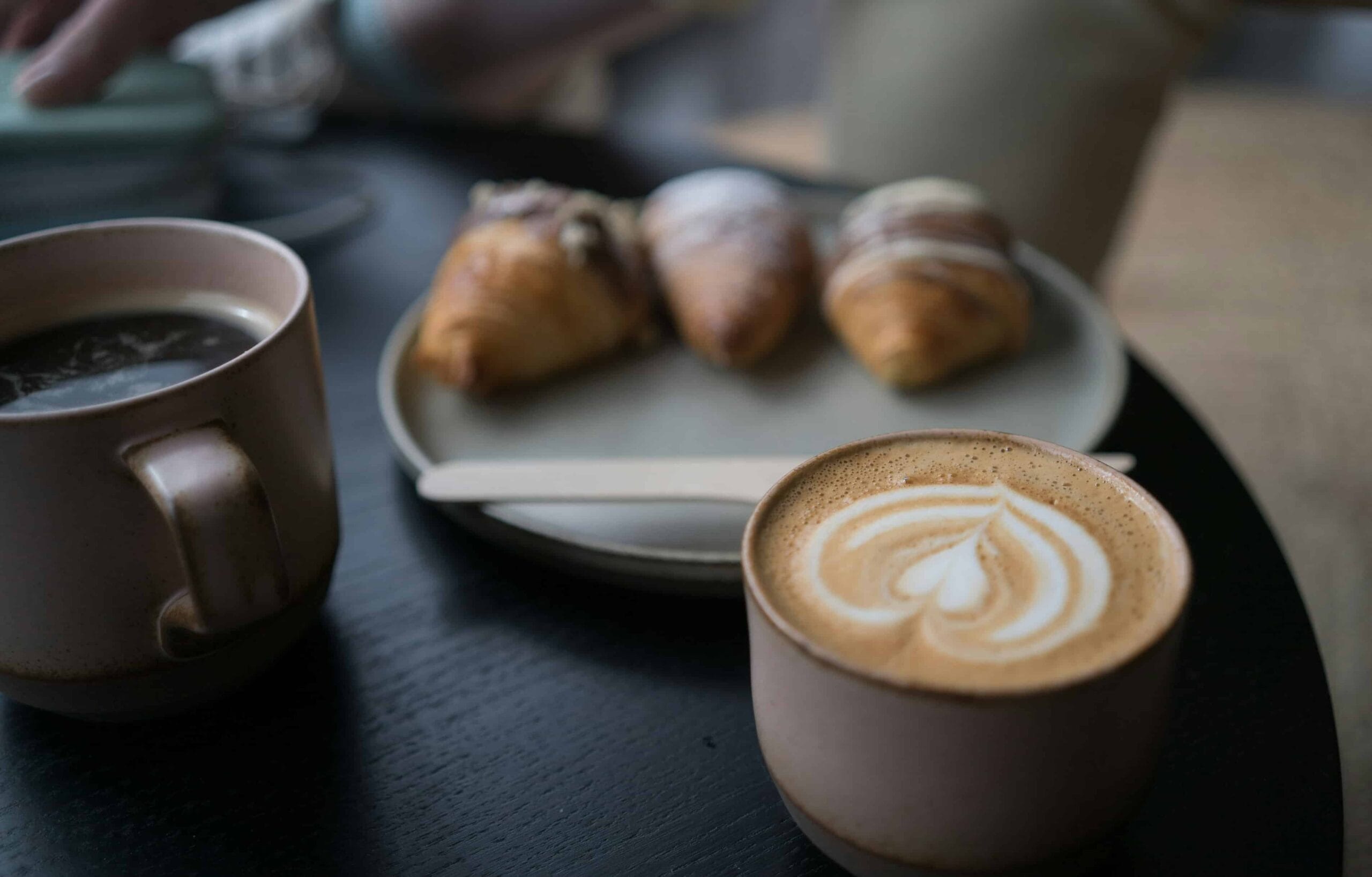 Kaffekoppar och croissanter på ett cafébord