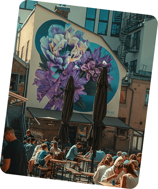 Gatuvy med uteservering framför en stor blomstermural