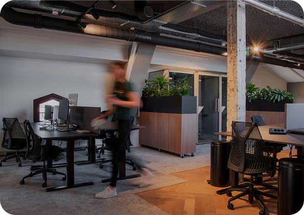 Öppen kontorsyta med arbetsplatser, växter och industriell inredning