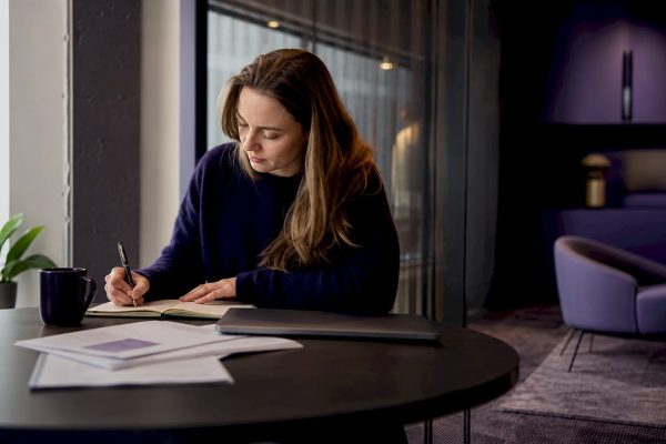 En kvinna sitter vid sitt skrivbord på kontoret och blickar ut över Göteborg genom fönstret.