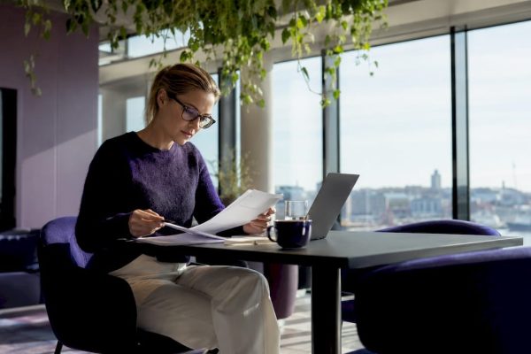 En kvinna sitter och jobbar på ett gemensamt kontor.