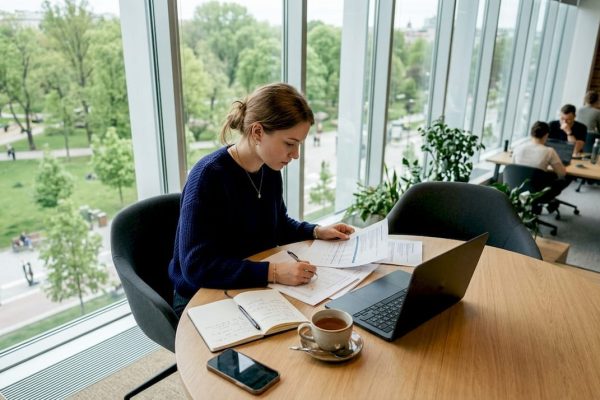 En entreprenör sitter och jobbar i en inspirerande coworkingmiljö, omgiven av andra kreativa människor.