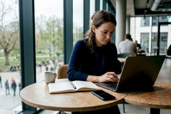 En kvinna sitter djupt koncentrerad med sitt arbete på ett modernt coworkingkontor mitt i stan.