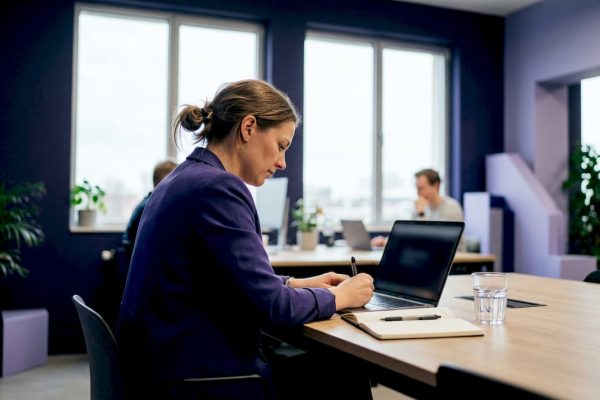 En kvinna sitter och jobbar vid sitt skrivbord på ett coworkingkontor.