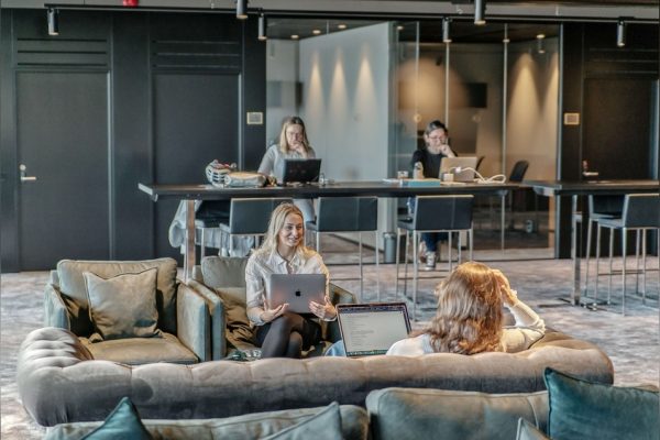 Members working in the lounge while others meet in the room behind