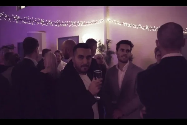 Guests mingling with drinks under string lights at an evening event